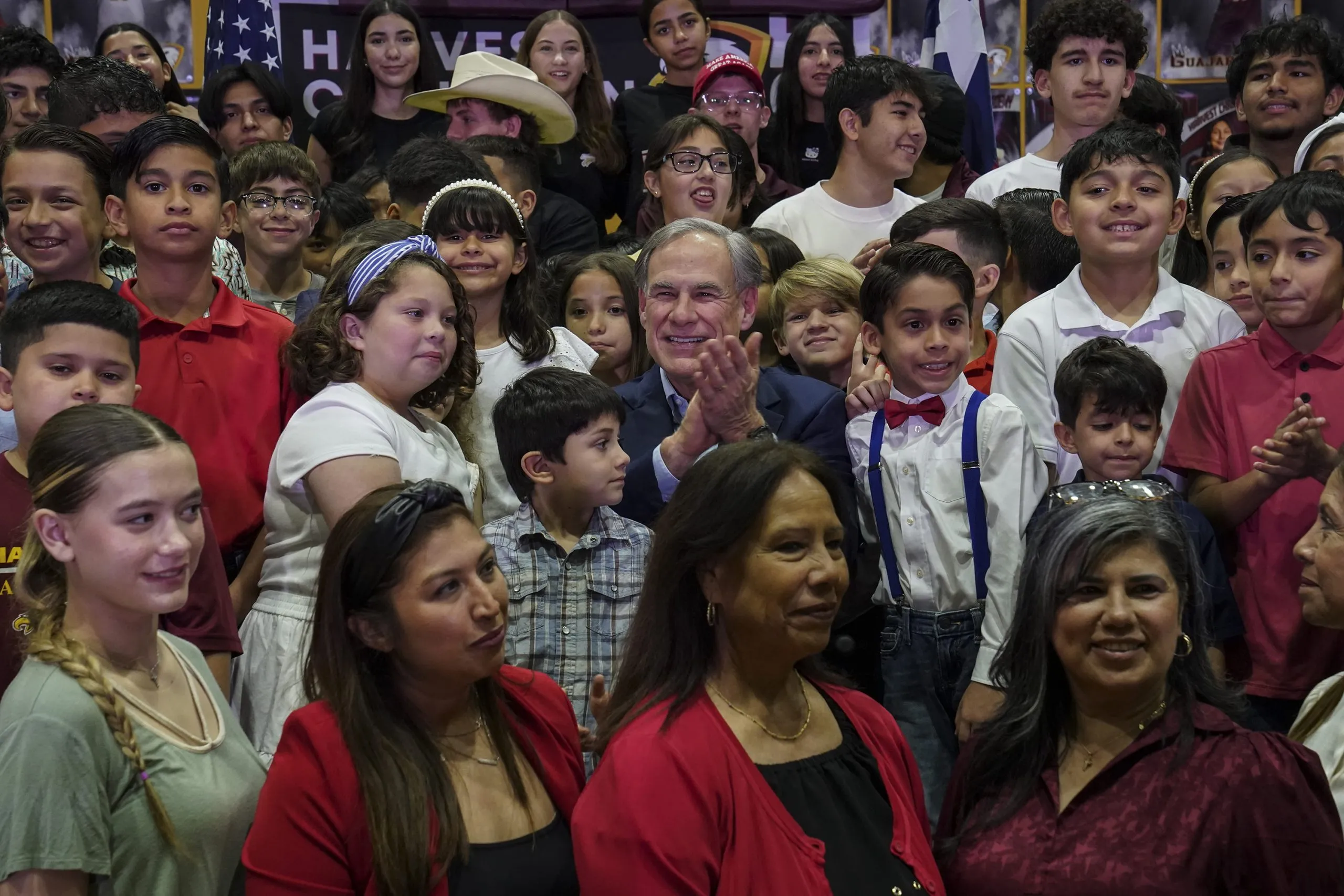 Gov. Greg Abbott takes a photo with students and staff after speaking about school vouchers at Parent Empowerment Night at Harvest Christian Academy in Edinburg